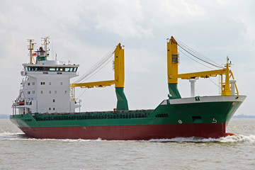 grünes Frachtschiff mit Kränen