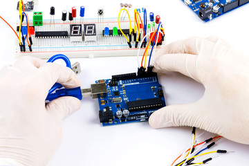 Engineer is connecting microchip to microcontroller with the help of usb cable. Top view. Engineer workplace