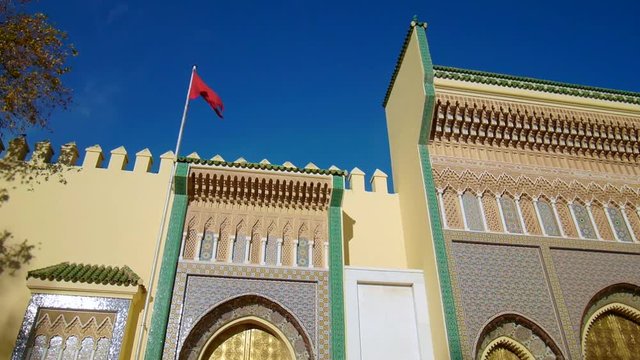 Close up of the Royal Palace of Fes (Dar el Makhzen), Morocco - golden doors, mosaics and red moroccan flag with wind. 