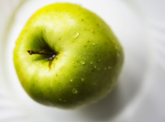 Closeup of fresh, autumn, yellow apple, Golden Delicious, freshly washed with water splashing in a white dish.