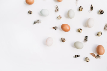 White and brown Easter eggs, quail eggs and feathers on white background. Flat lay, top view. Traditional spring concept.