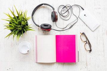 Flat lay of headphones with mobile phone on white wooden background