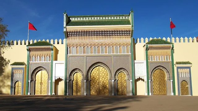 Front view of the Royal Palace of Fez (Dar el Makhzen), Morocco - golden doors, mosaics and red moroccan flag with wind. 