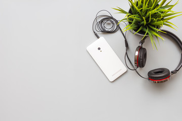 Flat lay of headphones with mobile phone on gray background