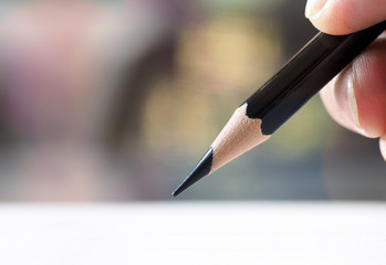 Woman hand holding pencil writing on papers with selective focus and blurred background