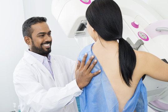 Smiling Doctor Assisting Woman Undergoing Mammogram X-ray Test