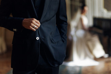 stylish handsome groom hand with silver ring on suit posing and elegant  bride playing the...