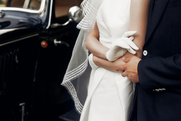 elegant gorgeous bride and stylish handsome groom holding hands close up, gentle touch. unusual...