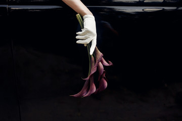 elegant gorgeous bride hand in silk glove holding wedding bouquet of callas  on backgound of...