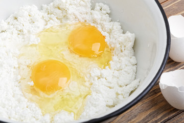 Bowl with cottage cheese and eggs on wooden table.
