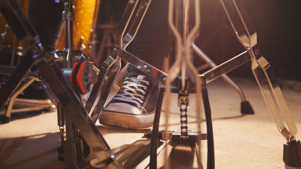 Drummer's foot in sneakers moving drum bass pedal - Powered by Adobe