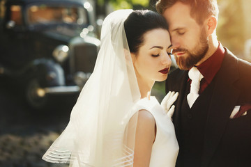gorgeous elegant bride and stylish groom embracing, gentle touch in sunny light. unusual luxury...