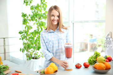 Young beautiful woman making fresh juice in kitchen