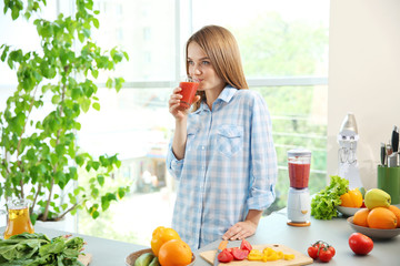 Young woman drinking fresh juice in the kitchen