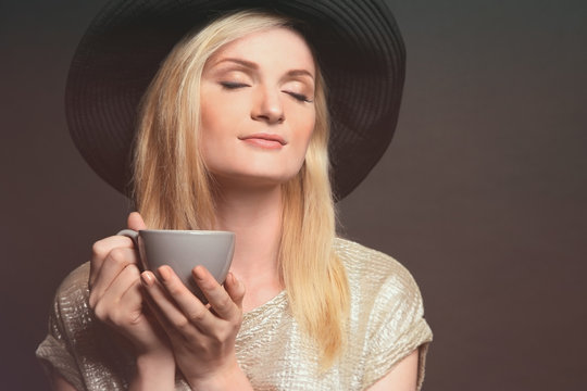 Beautiful girl with cup of coffee on dark background