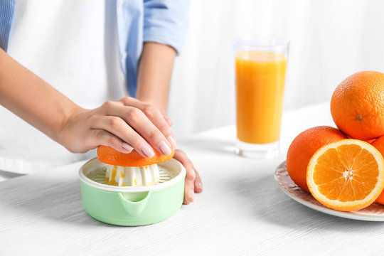 Female hands squeezing orange juice, closeup
