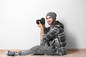 Handsome young photographer on light wall background