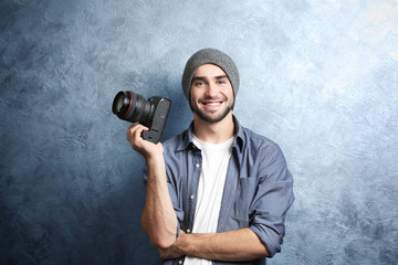 Handsome young photographer near grey textured wall - obrazy, fototapety, plakaty