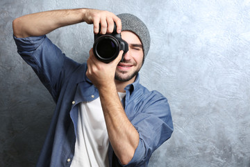 Handsome young photographer near grey textured wall