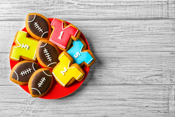 Plate with creative cookies decorated in football style on wooden background