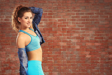 Beautiful young hip-hop dancer near brick wall