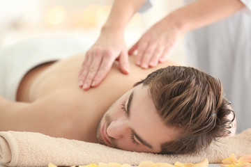 Obraz na płótnie Canvas Young man having massage in spa salon