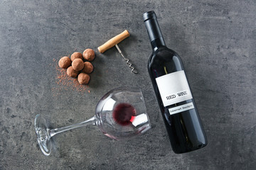 Composition of tasty truffles, wine bottle and glass on grey background