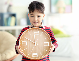 Cute little boy with big clock at home