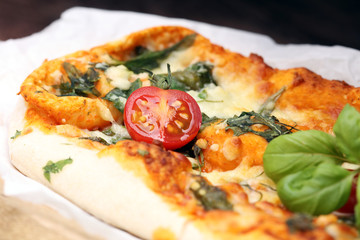 Hot pizza slice with melting cheese on a rustic wooden table.