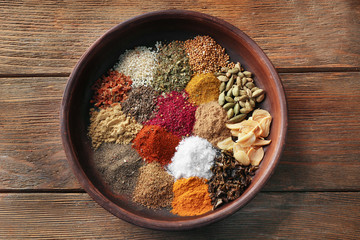Plate with aromatic spices on wooden background