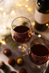 Glasses of red wine and chocolate truffles on decorated table closeup