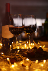 Glasses of red wine and chocolate truffles on decorated table closeup