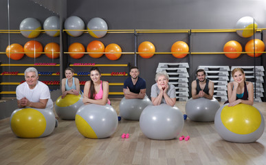 People of different ages training with fit balls in gym