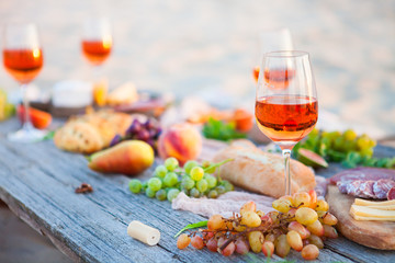 Picnic on the beach at sunset in boho style, food and drink concept