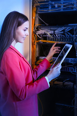 Beautiful young engineer with tablet computer in server room
