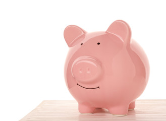Pink ceramic piggy bank on wooden table