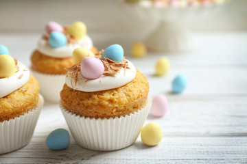 Tasty Easter cupcakes on white wooden table