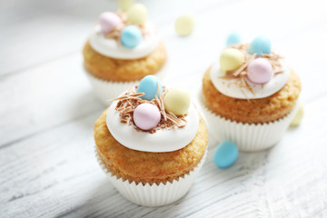 Tasty Easter cupcakes on white wooden table