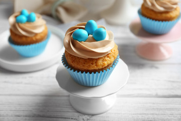 Cake stand with delicious Easter cupcake on white wooden table