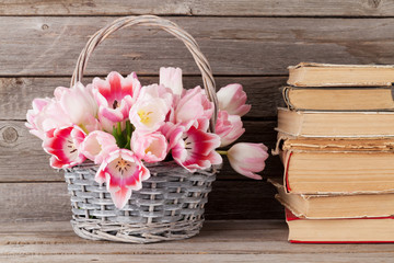 Pink tulips bouquet basket and old books