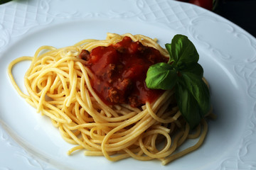 Plate of delicious spaghetti Bolognaise or Bolognese with savory minced beef and tomato sauce garnished with parmesan cheese and basil