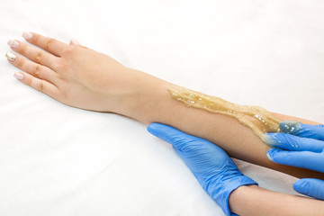 Epilation sugar processes woman passes in a beauty salon 