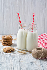 Bottles of milk and chocolate chip cookies on wooden background