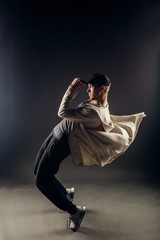 A beautiful young hip hop dancer dancing contemporary urban street dance in empty clear grey wall...
