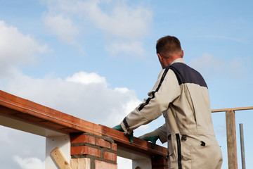 bricklayer mason puts a lintel on a wall outdoors