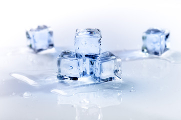 Iced cubes melting on a white table with reflection. Water. Melting of ice.