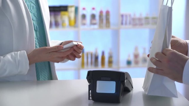Woman paying through smartphone using NFC technology. Close up.