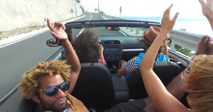 Handsome black man sticking his feet up of the convertible riding with friends