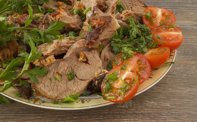 Sliced lamb with tomato and greens on a plate