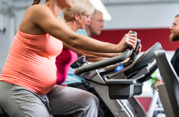 Fototapeta na wymiar Schwangere Frau beim Spinning im Fitnessstudio